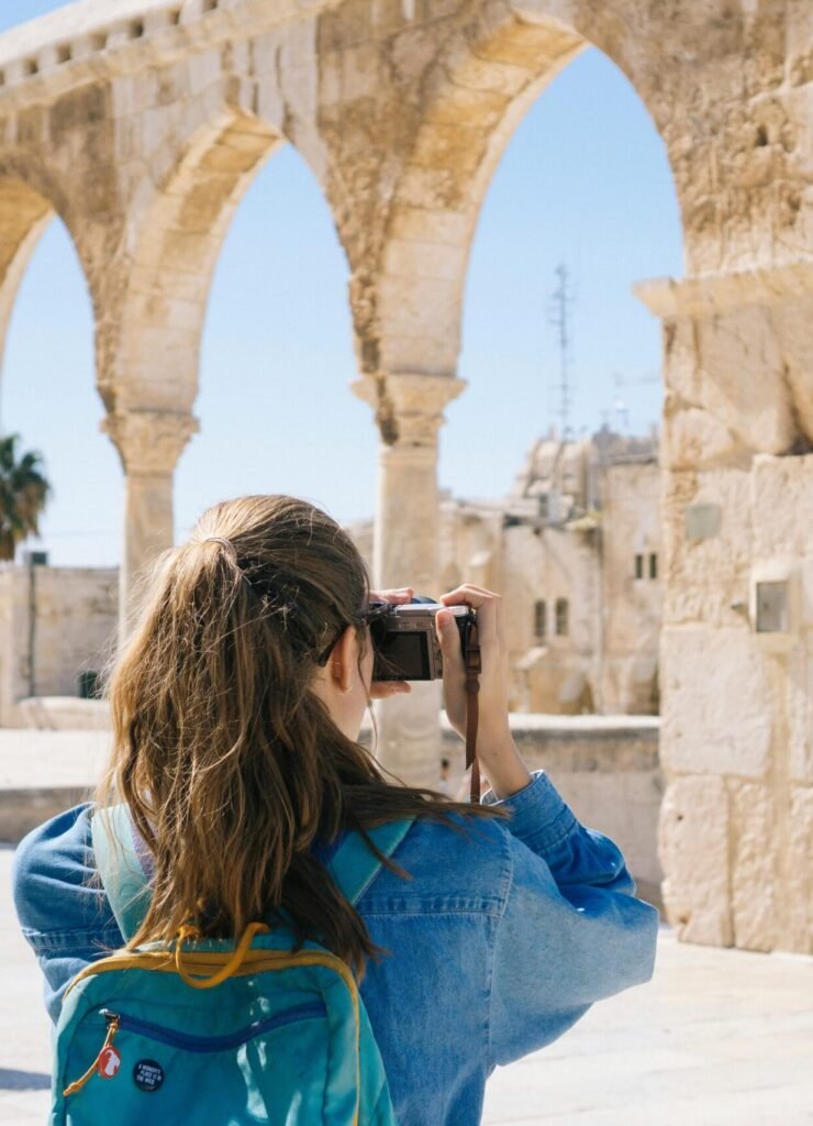 A tourist photographs the ancient stone arches in Jerusalem's Old Town, capturing the essence of travel and history.